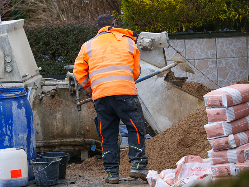 Mitarbeiter eines Bauunternehmens mischt Estrich Sand in Estrichmaschine